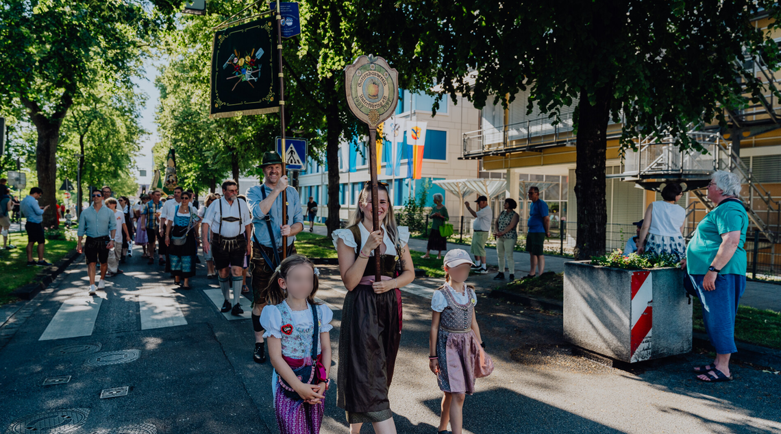 Personen laufen mit Fahnen beim Festumzug mit.