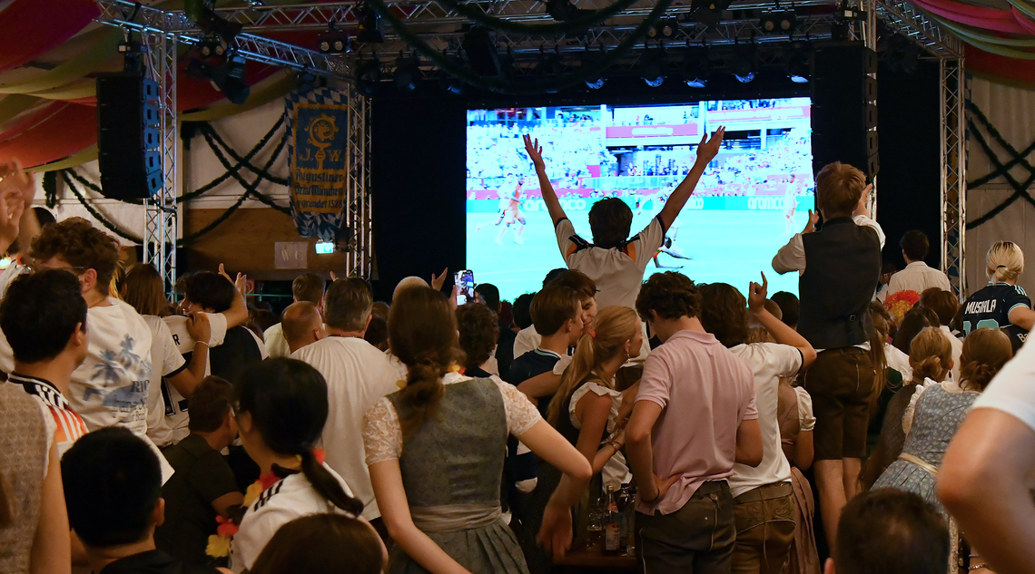 Jubelnde Menschen vor einer großen Leinwand.