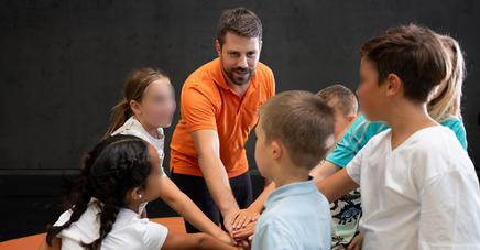 Kinder stehen im Kreis und mit ausgestrecken Händen