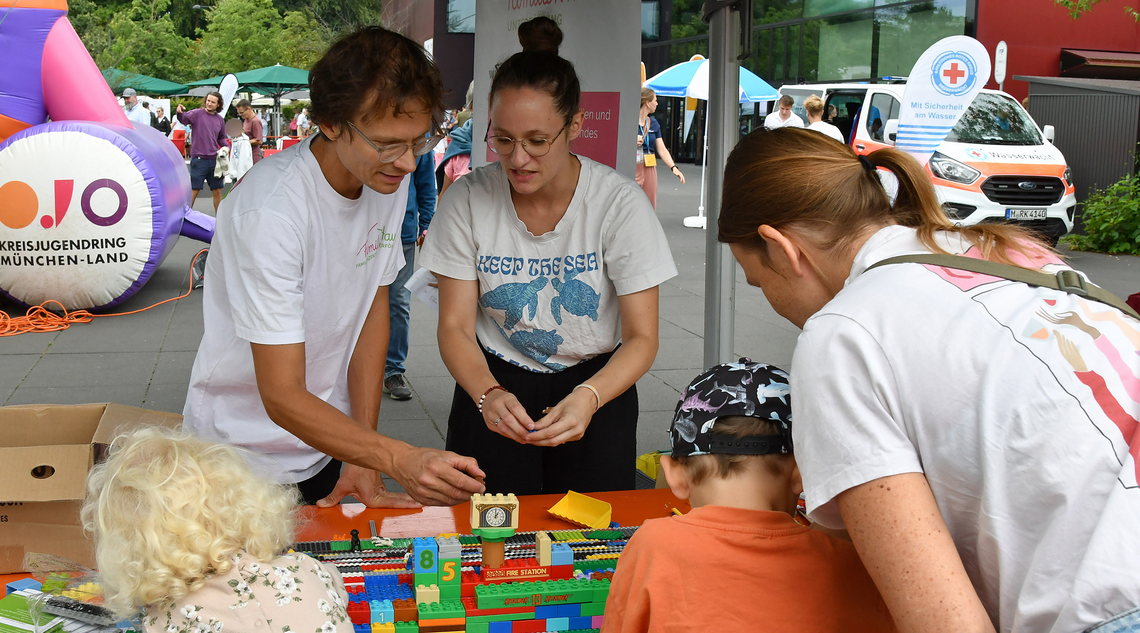 Mehrere Personen stehen am Stand und bauen mit Lego.