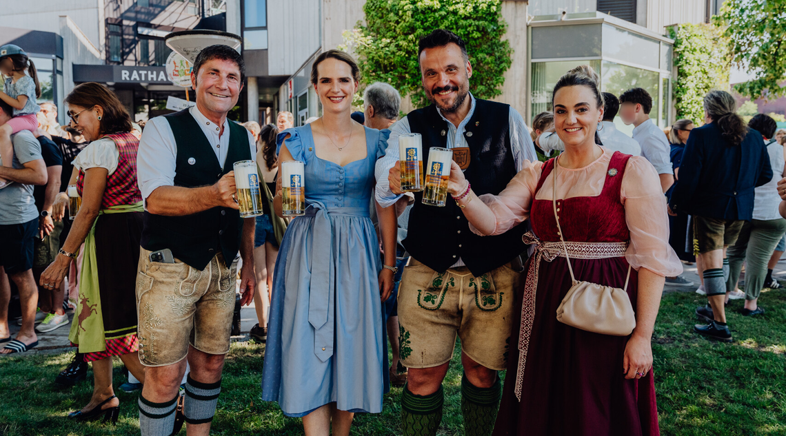 Vier Personen beim Anstoßen mit Bierkrügen