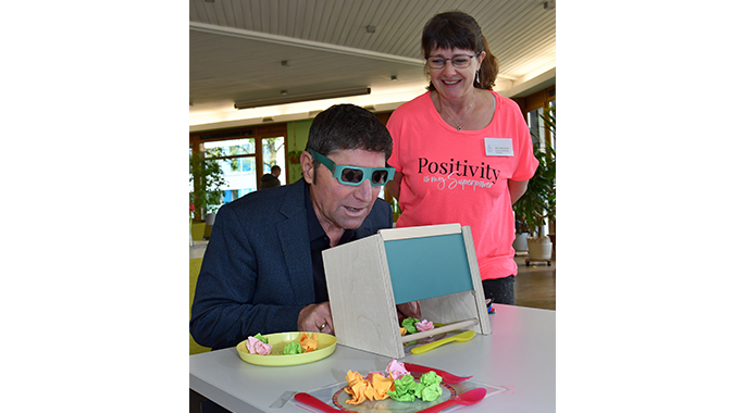 Bürgermeister Andreas Kemmelmeyer trägt eine Brille und schaut in eine Spiegelbox.